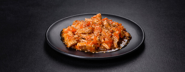 Teriyaki chicken with sauce, sesame, herbs and spices on a dark background