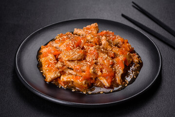 Teriyaki chicken with sauce, sesame, herbs and spices on a dark background
