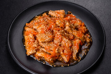 Teriyaki chicken with sauce, sesame, herbs and spices on a dark background