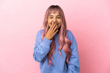 Young mixed race woman with pink hair isolated on pink background happy and smiling covering mouth with hand