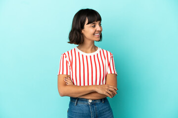 Young mixed race woman isolated on blue background with arms crossed and happy