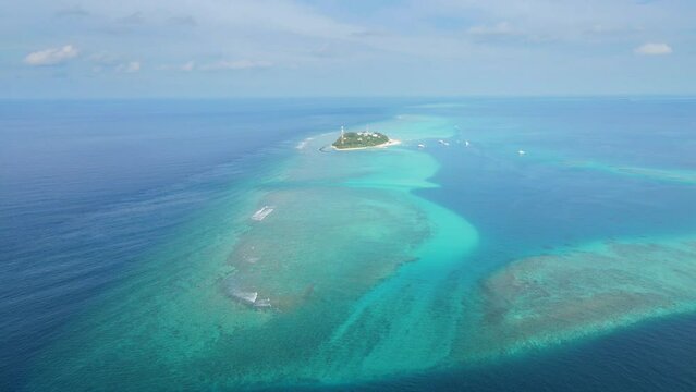 Tropical atoll island in Maldives with coral reef and turquoise sea water. Touristic vacation holidays travel destination. Scenic seascape. Drone aerial video footage. Fulidhoo, Vaavu.