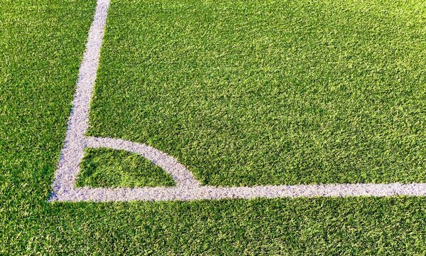 Detail view of the corner in a green football field made of artificial grass