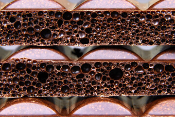 Porous dark Chocolate bar closeup. Porous chocolate macro view. Copy space. Vertical orientation