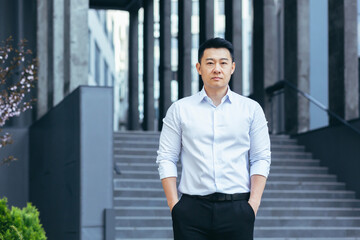 Fototapeta premium Portrait of serious asian businessman, man outside office looking at camera