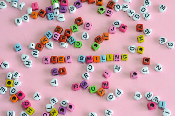 Keep smiling words formed with letter blocks in different colors on a pink surface