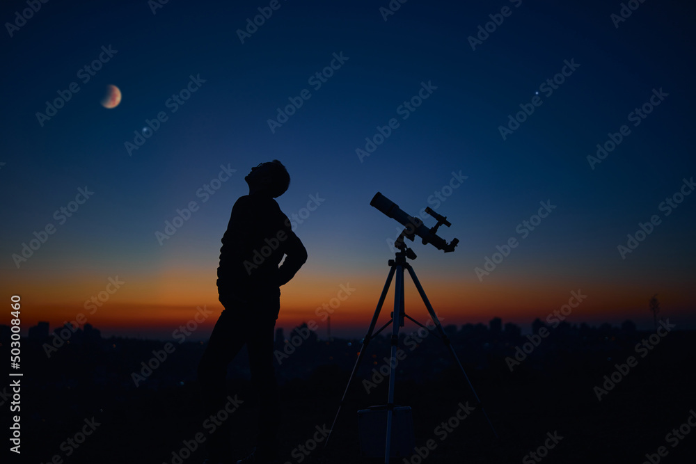 Wall mural silhouette of a man and telescope under the starry skies.