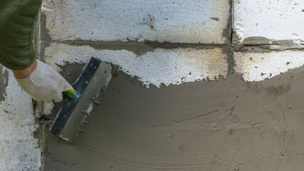Plastering cement at wall for renovation house. Plasterer smoothing plaster on wall. Putty brick wall background