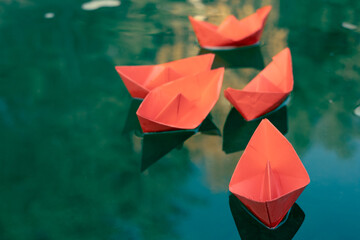 flotilla of red paper ships on the water surface