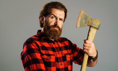 Serious man with axe. Bearded lumberjack with ax. Male in checkered shirt with hatchet. Logger tool.