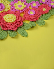 Handcrafted flowers and leaves on a yellow paper background.
