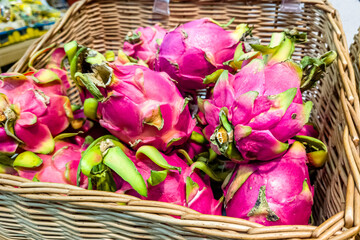 A photo of Dragon fruits in green baskets for sale in a supermarket, close up