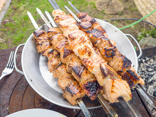 Grilled salmon fish kebab skewers on wooden board. Dark wooden background.