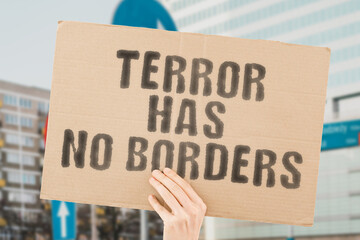The phrase " Terror has no borders " is on a banner in men's hands with blurred background. Terrorist. Army. Assault. Frighten. Head. Male. Anger. Afraid. Dangerous. Crime. Offense. Evil. Violation