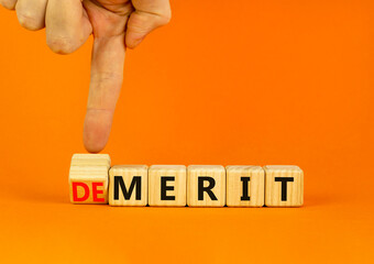 Demerit or merit symbol. Businessman turns wooden cubes and changes the concept word Demerit to...