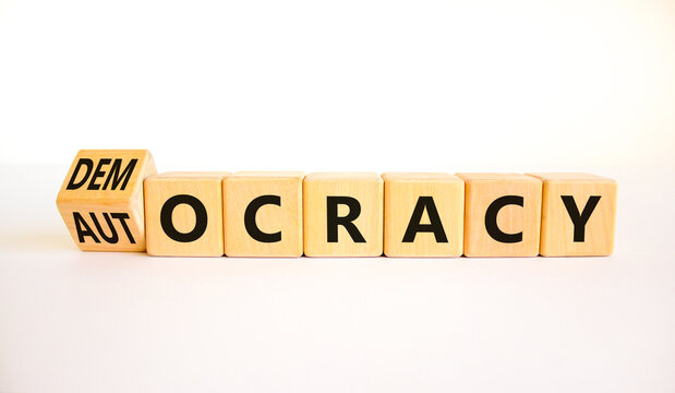 Democracy or autocracy symbol. Turned wooden cubes and changed the concept word Autocracy to Democracy. Beautiful white background. Copy space. Business democracy or autocracy concept.