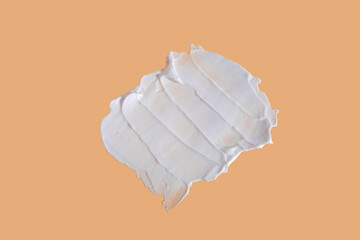 White smear of cosmetic cream on a beige background. Creamy foundation texture isolated. Smear of face cream. Close up of cream texture