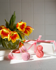 sweet pasta in the form of the number eight on the table. There are other macaroons nearby. Horizontal frame. Side view. A large frame with tulips in a vase