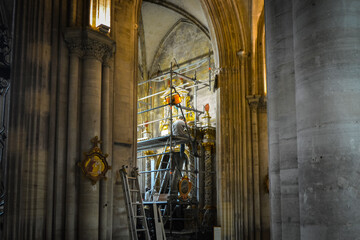 A male art restorer sits on a scaffold as he works on a wall at the Our Lady of Bayeux Cathedral in...