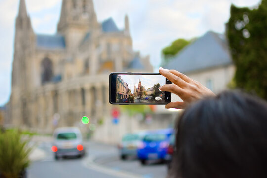 A woman takes a photograph with a smart phone of the Our Lady of Bayeux cathedral in Bayeux, France.
