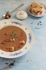 Bean soup on a plate with bread and a sprig of rosemary, a composition in a rustic style on a light blue background, mediterranean cuisine.