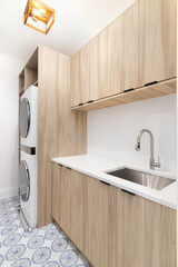 A new laundry room with wood cabinets, a white marble countertop, patterned tile floor, white...