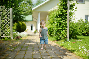 Fototapeta na wymiar Funny toddler boy having fun outdoors on sunny summer day. Child exploring nature.