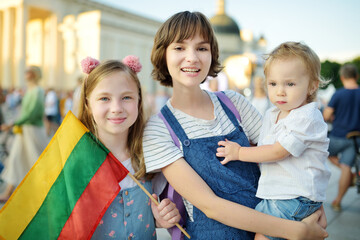 Two big sisters and a cute toddler boy holding tricolor Lithuanian flag on Lithuanian Statehood Day, Lithuania