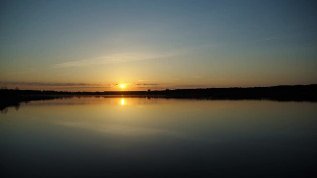 Sun slowly moving over the horizon calm evening with beautiful reflection in lake