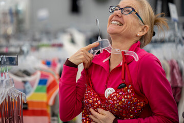 Pretty mature middle age woman shopping for clothes in a bright airy store.