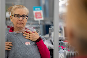 Pretty mature middle age woman shopping for clothes in a bright airy store.