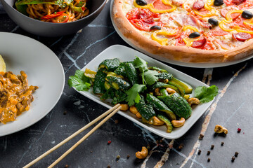 salad with broken cucumbers and peanuts and cashew on black marble