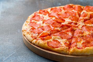Pepperoni pizza on the board on dark blue stone table macro close up