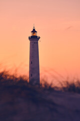 Lighthouse in warm morning glow above the dunes. High quality photo - obrazy, fototapety, plakaty