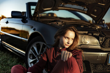 A beautiful girl near a car broken down in a field, a retro conv