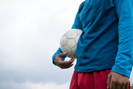 Fototapeta Man holding a white soccer ball in a cloudy day at park