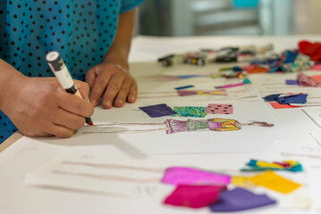 Close up of a fashion designer drawing sketches on her desk