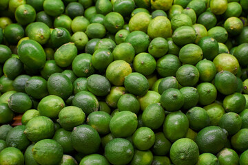 Green lemons placed on a shelf for sale at a market