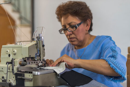 Mature latin seamstress using a sewing machine stitching fabric pieces
