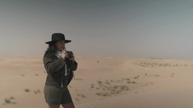 Arabic female traveler taking photos with film camera in the desert