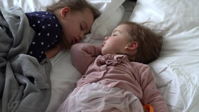 Authentic Two Cute Little Girls Sister Sleeping Sweetly Together In Comfortable White Bed. Beautiful Tired Child Have Rest Time Gently Soothing. Kids Resting. Care, Childhood, Parenthood, Life concept