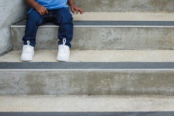 Obraz na płótnie Canvas A toddler boy sitting on conncrete steps with empty copy space
