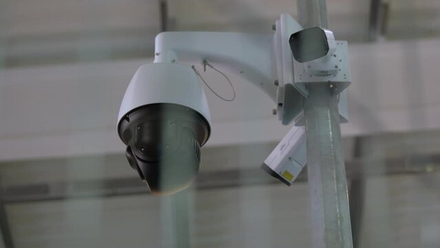 Black surveillance video camera turning to the right. Control camera rotation.