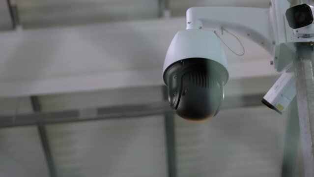 Close-up of surveillance security video camera rotating to the right. Security system concept.