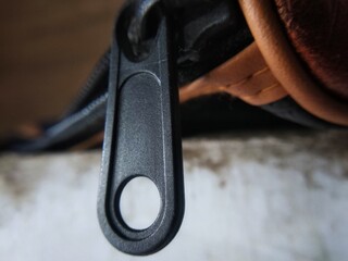 Metallic zipper pull hanging on leather wallet