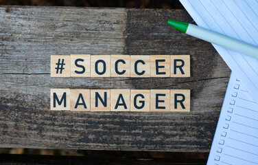 Wooden toy blocks with the text Soccer Manager on it with pen and paper in the background
