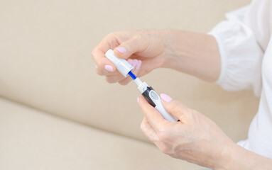 Woman taking blood sample from her finger for glucometry. Diabetes. Glucose control. Glucometer.
Blood glucose level. Device with lancet for glucometry.