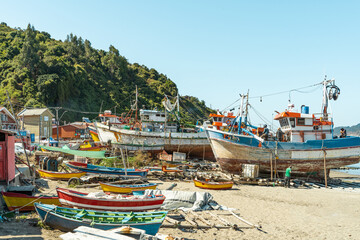 Boats under repair in Caleta Tumbes with beach and small boats underneath, Chile