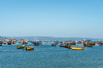 Fototapeta na wymiar Horizontal shot of colorful boats in Caleta Tumbes with mountains in the background, Chile