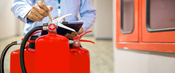 Fire extinguisher has engineer inspection checking pressure gauges of fire extinguishers to prepare fire equipment for protection prevent emergency and safety rescue and alarm system training concept.